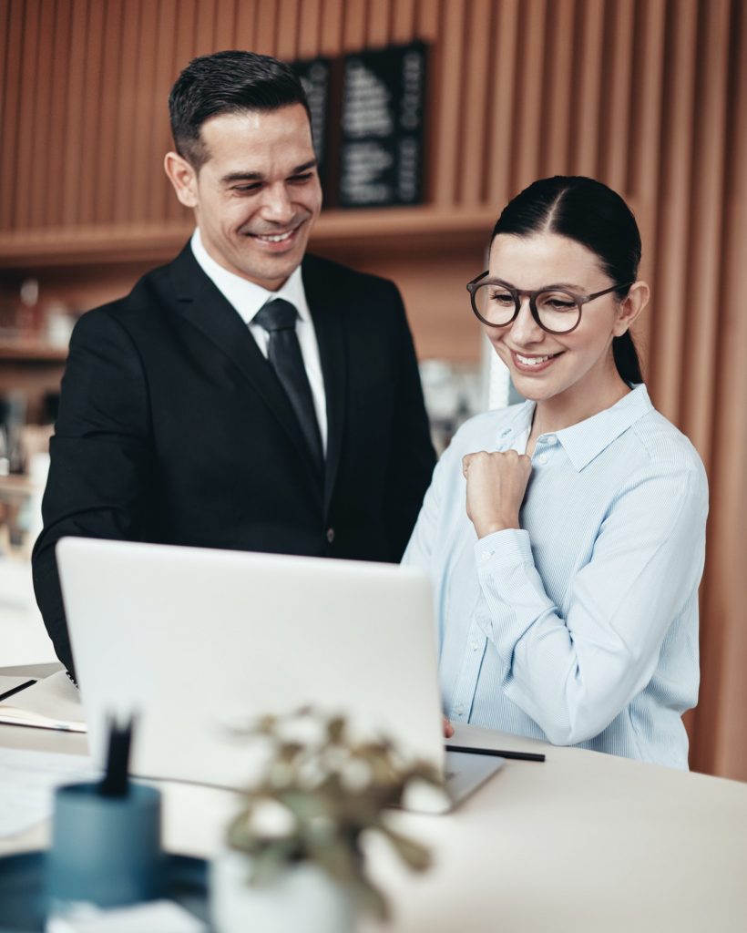 two-smiling-businesspeople-using-a-laptop-together-in-an-office.jpg