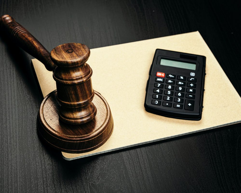 Wooden judge's gavel and calculator on table